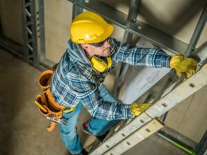 Man wearing gloves and a utility belt climbs up the rungs of an extension ladder