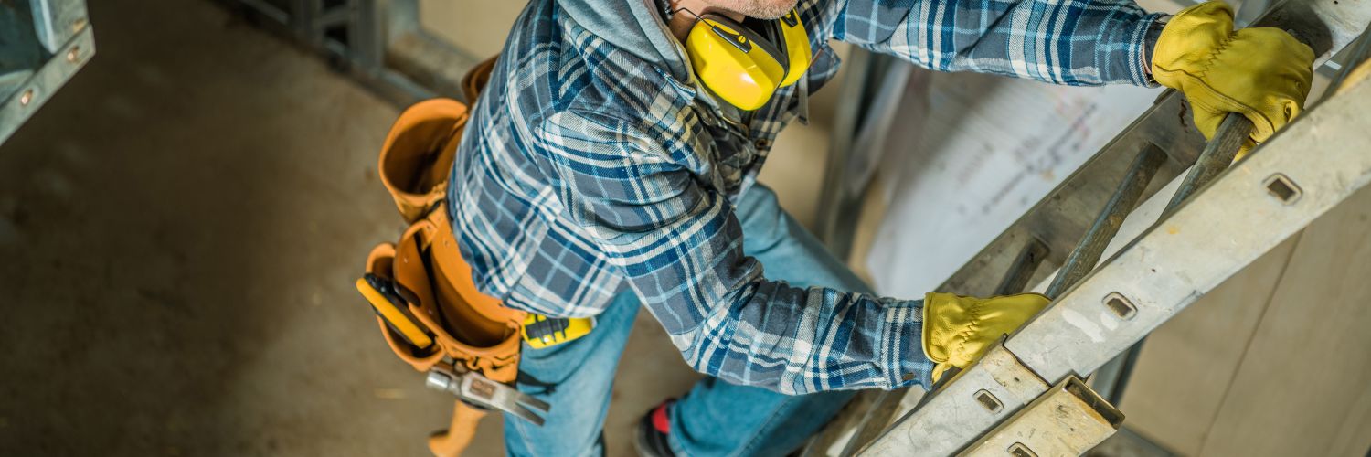 Man wearing gloves and a utility belt climbs up the rungs of an extension ladder